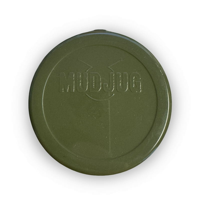 An olive green circular plastic lid embossed with the text 'MUD JUG' and a stylized face, shown on a plain white background with a drop shadow.